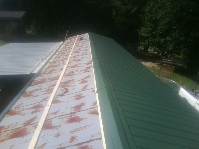 Old rusted panels beside newly installed green metal roofing — Wind Damage Roof Repair by Roofing Brothers in Pawcatuck