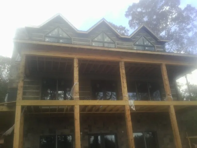 Dormers and porch framing on a large log home under construction — Roof Coating work by our crew in Pawcatuck