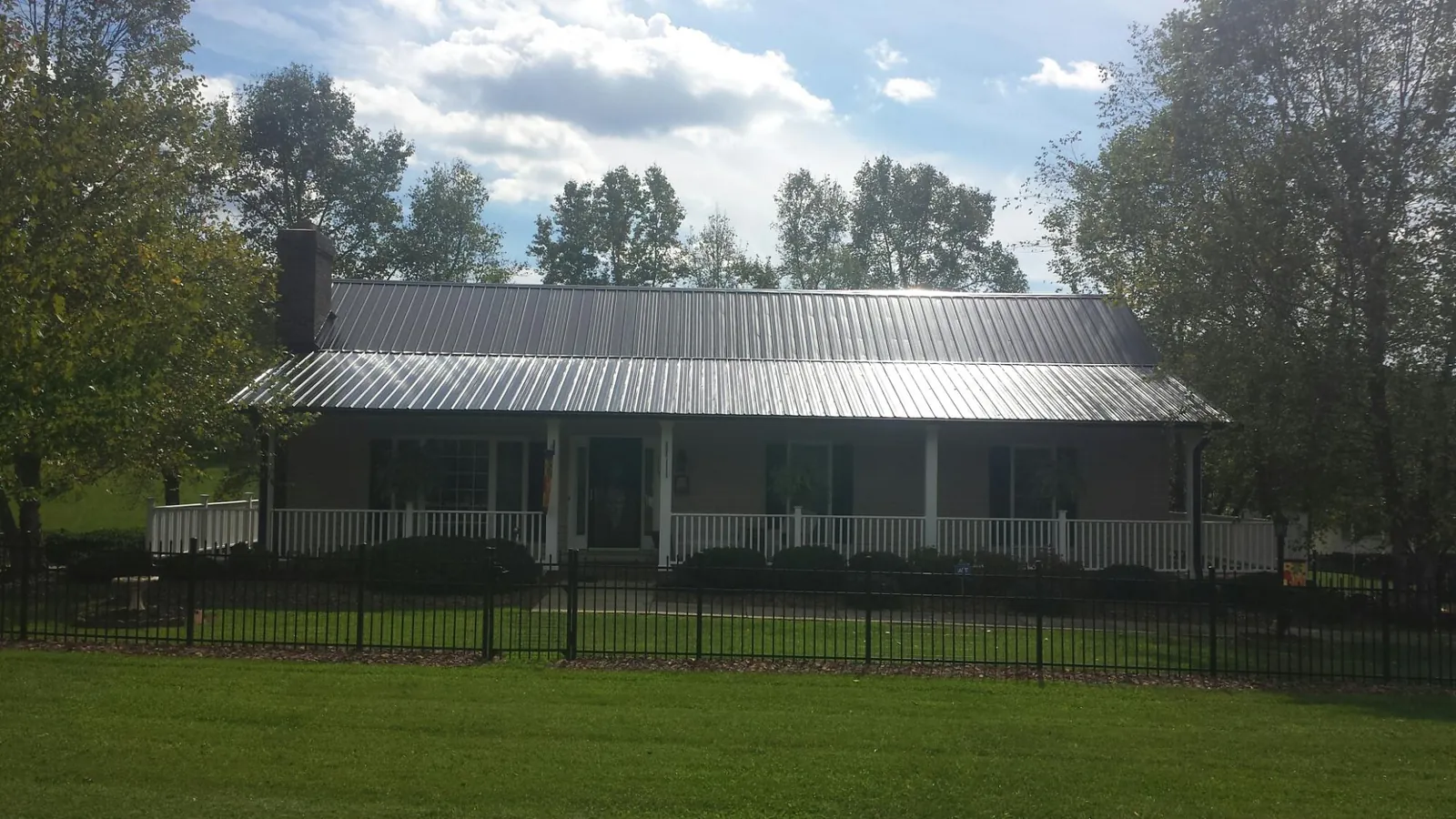 Gray metal roof on a brick ranch with a full width front porch — Gutter Guard Installation work by our crew in Pawcatuck