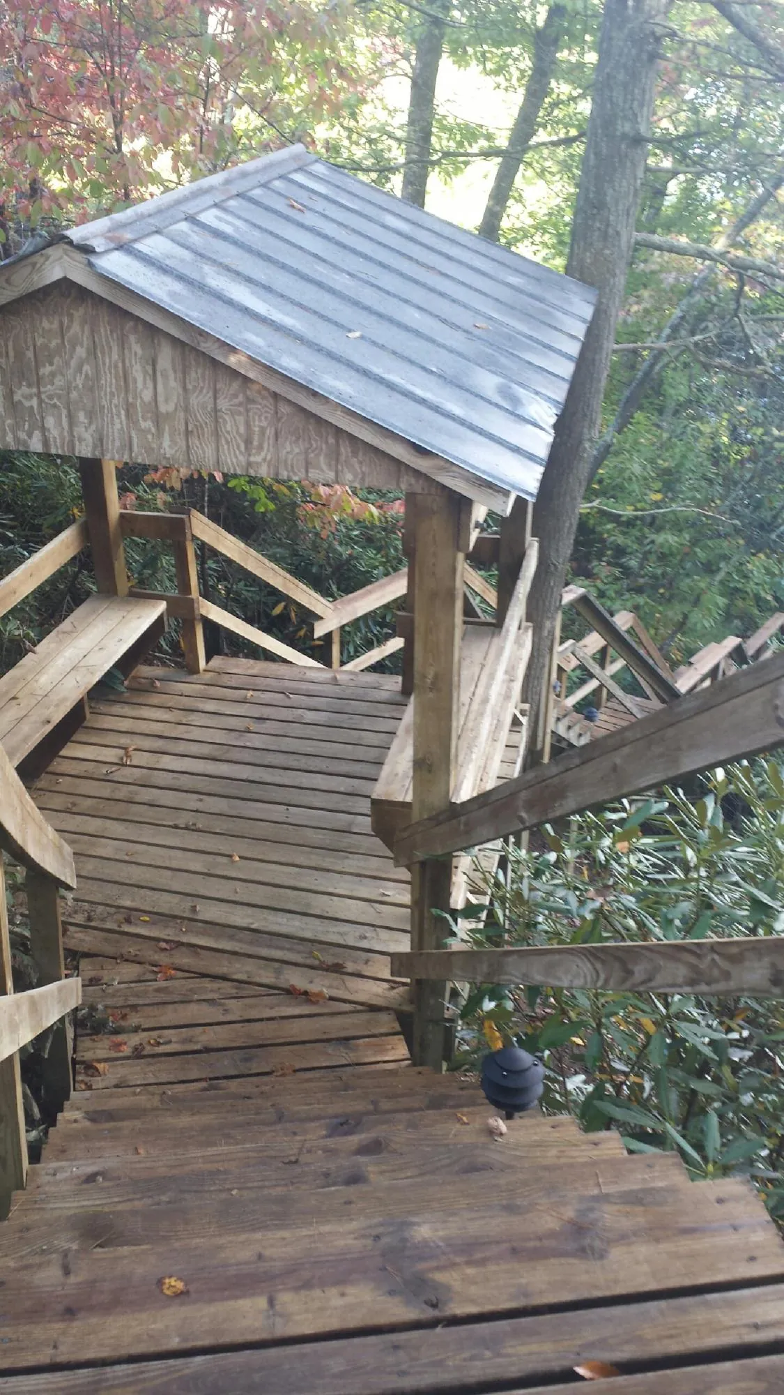 Metal roofed shelter over wooden steps on a wooded walkway — Skylight Repair & Installation work by our crew in Pawcatuck